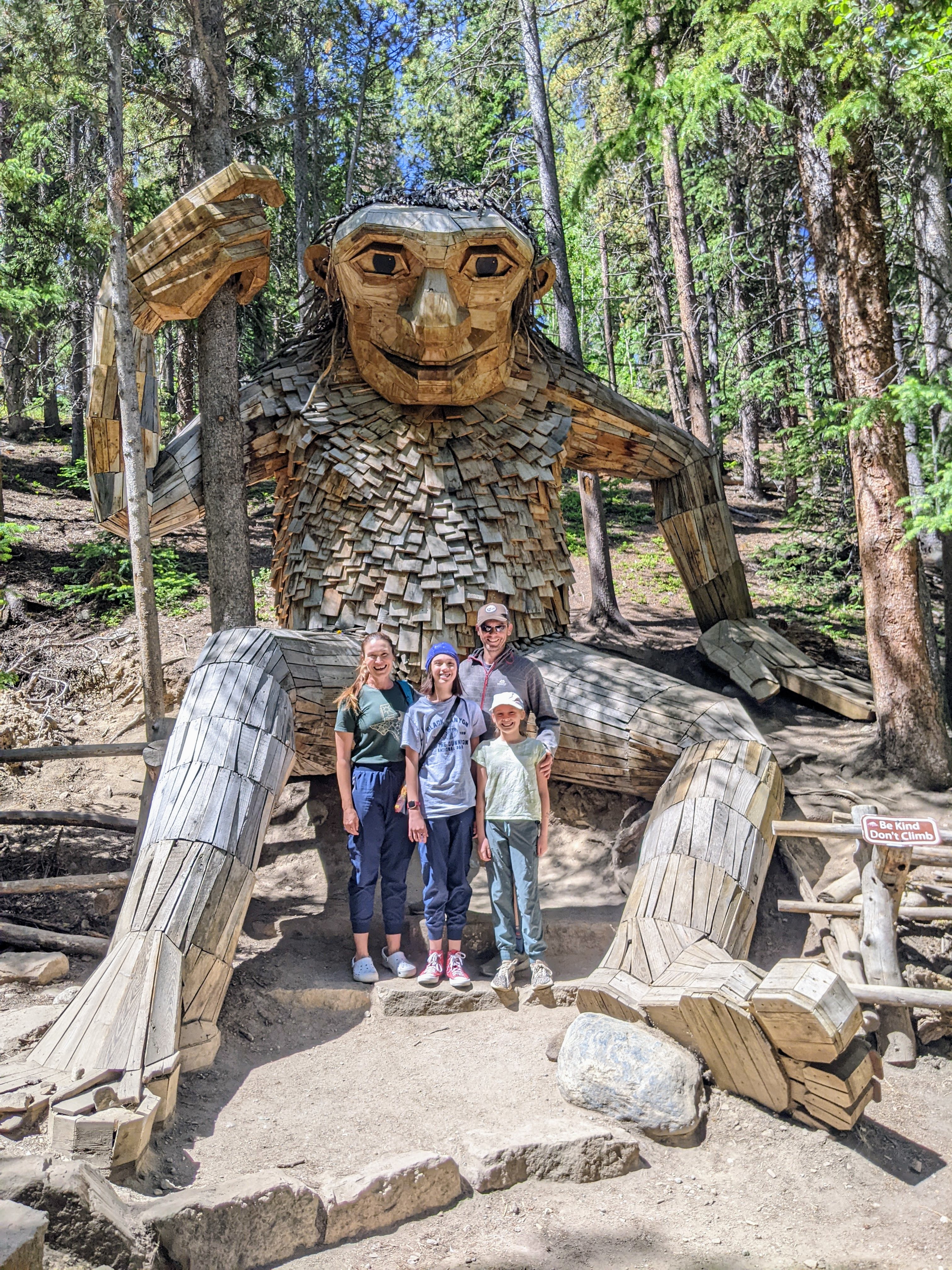 Family standing in front of the giant wooden troll sculpture Isak Heartstone in Breckenridge, Colorado