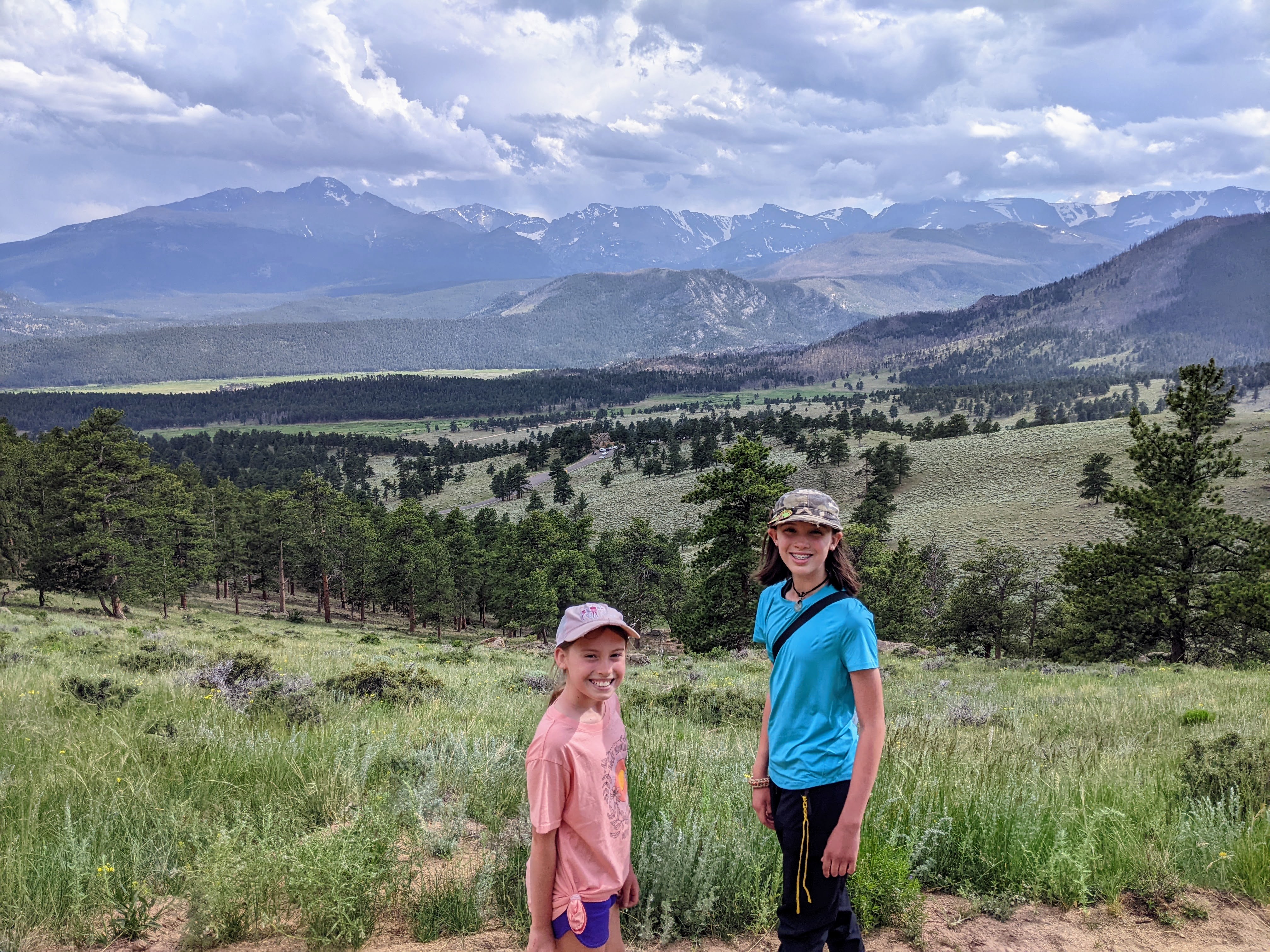 Two girls standing on Deer Mountain in Rocky Mountain National Park with mountain views in the background