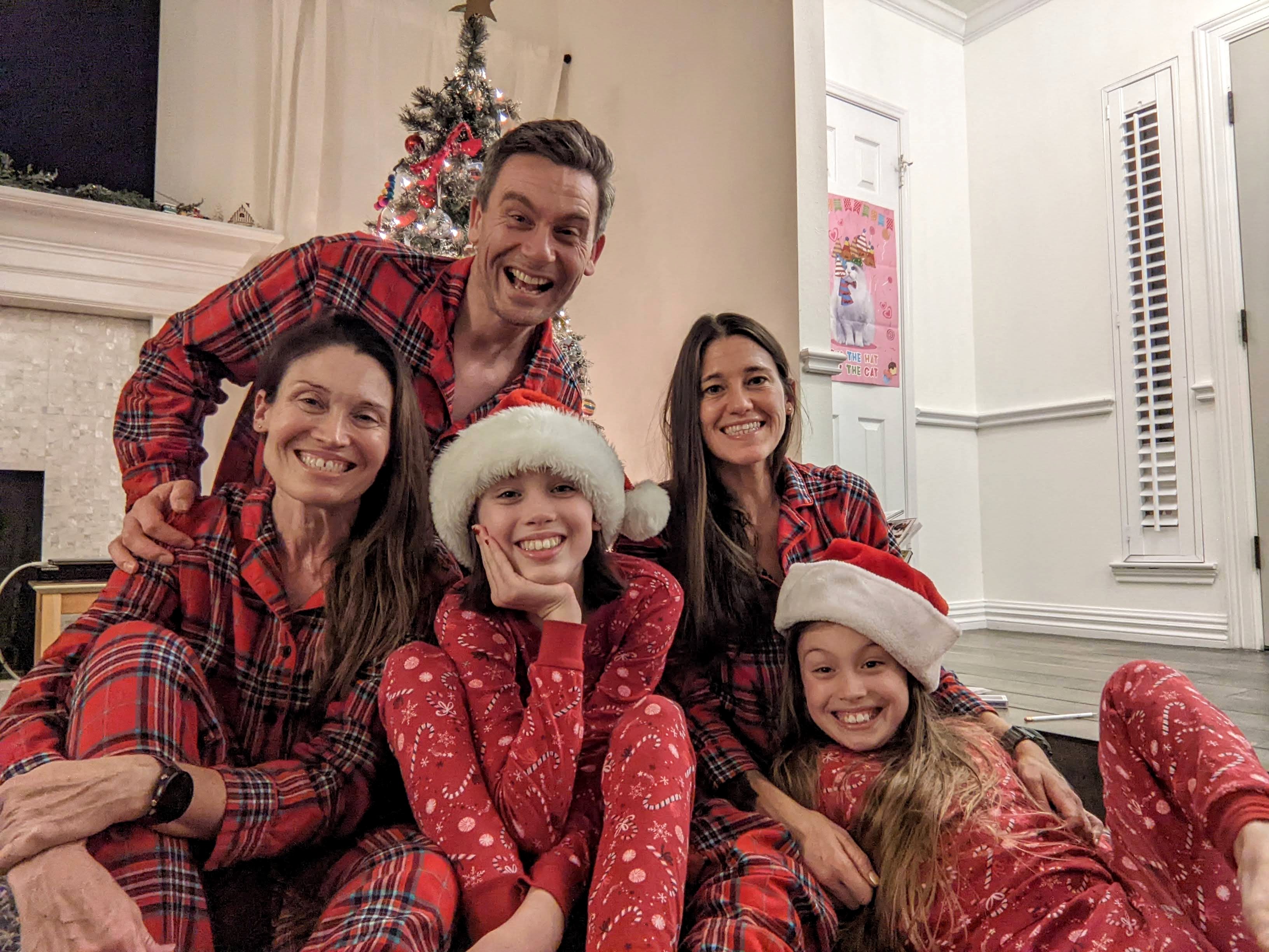 Family in Christmas pajamas smiling together in the living room with gifts, perfect for a holiday gift guide for families who love the outdoors.