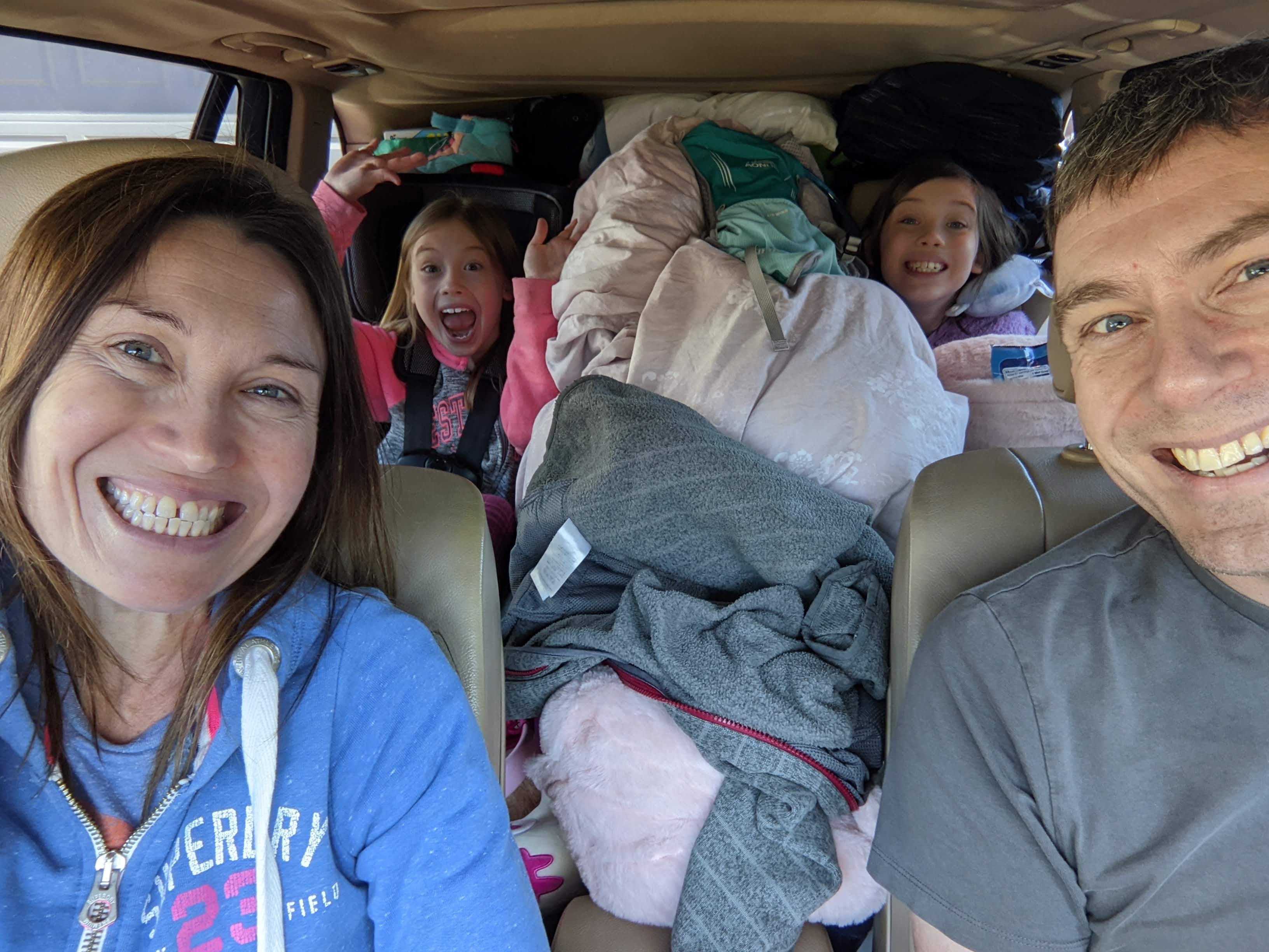 Family road trip selfie with kids sitting in a packed car ready for travel