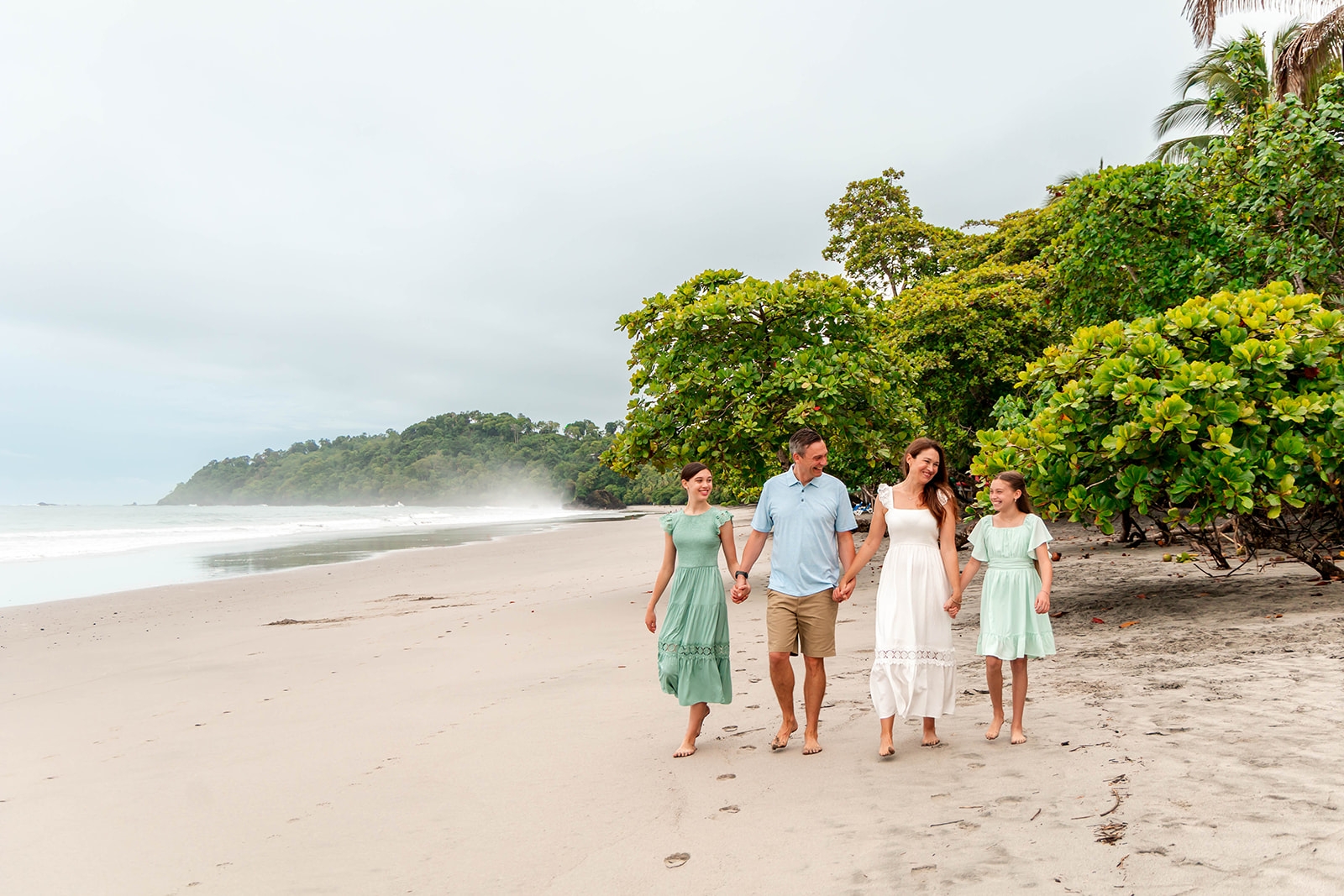 Family of four walking together along a tropical beach in Costa Rica, representing family travel adventures and outdoor vacations.